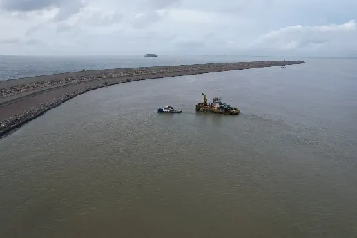 Work vessel with a crane towing a smaller boat on a calm waterway.