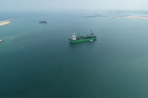 A work vessel in the middle of the ocean surrounded by land.