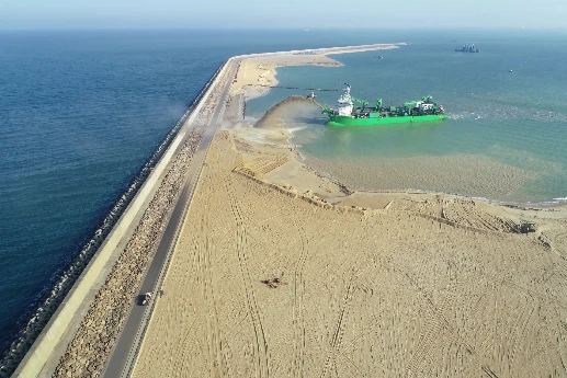 Dredging vessel spraying sand onto a shoreline.