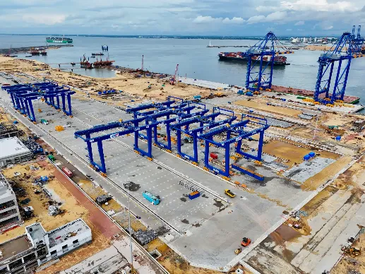Cranes and container yard at CWIT with container vessels in the sea.