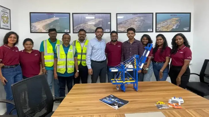 CWIT team behind a meeting table with a quay crane model on it.